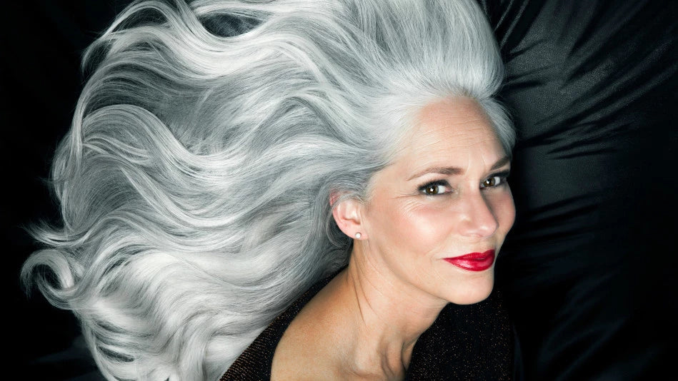 woman laying down on bed showing off long silver hair