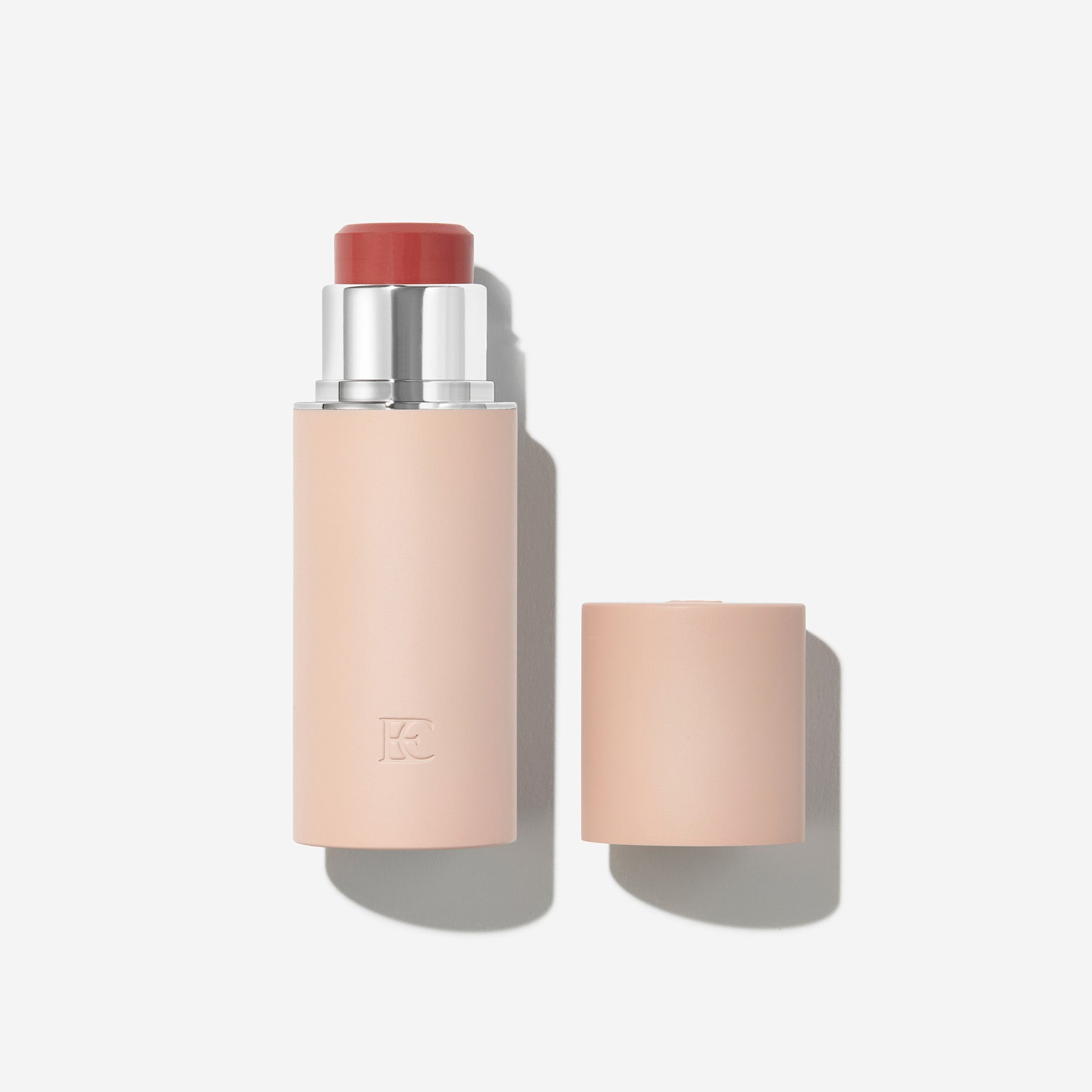 A blush stick with a beige cap on a light background.